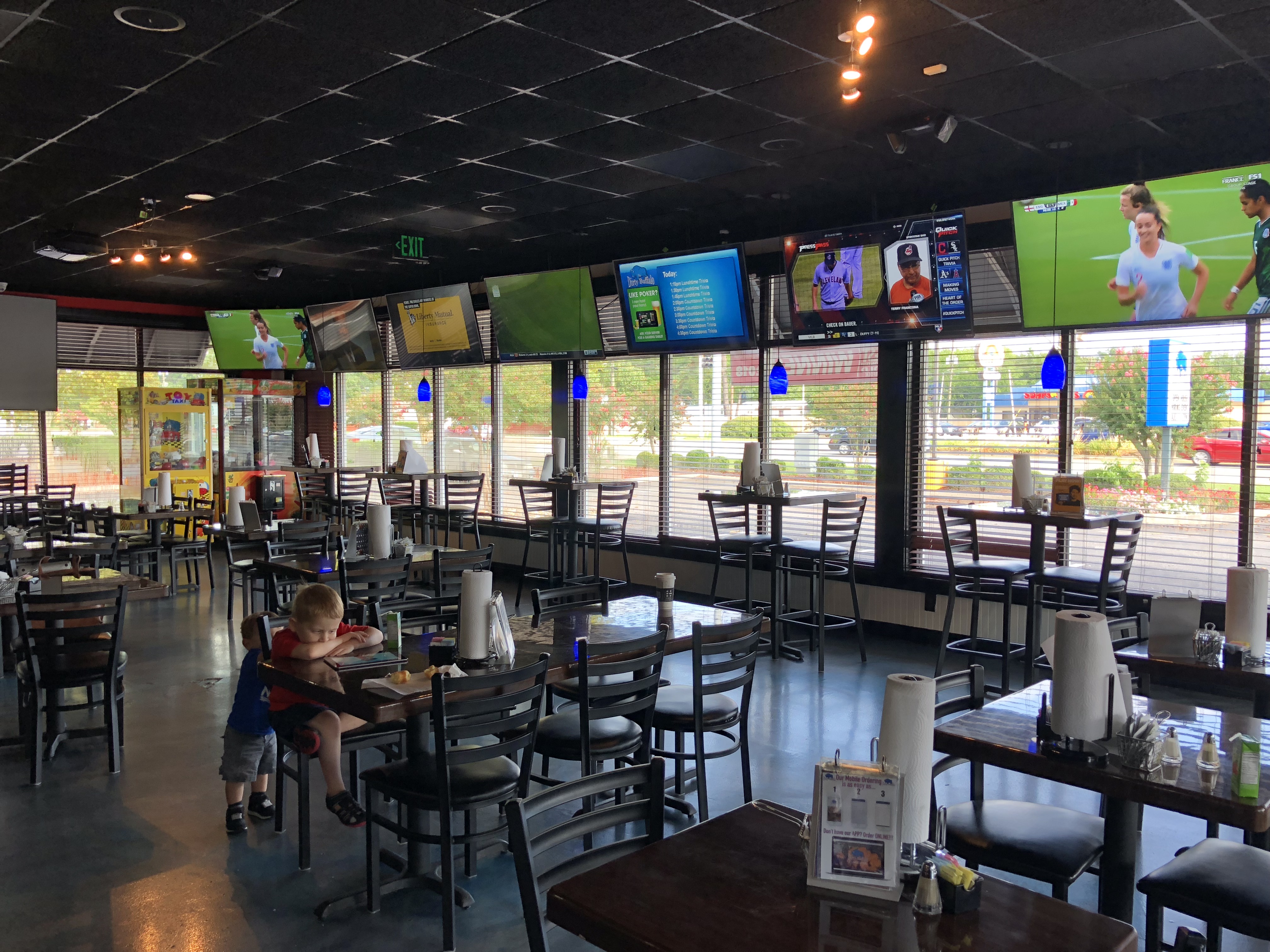The Little Creek dining room with kids at a table, window seating and TVs overhead