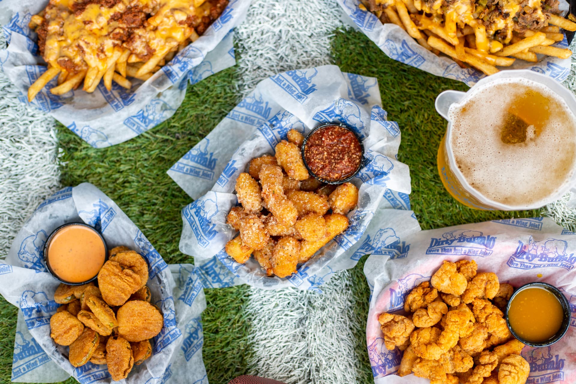 A spread of Dirty Buffalo appetizers — loaded fries, cheese curds, fried pickles and cauliflower bites
