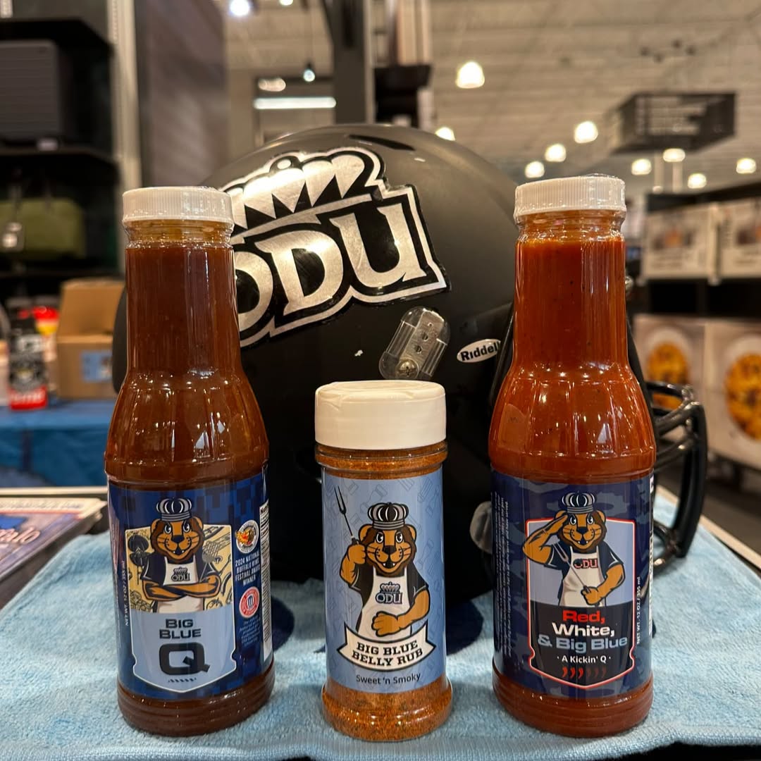 Three bottles of Dirty Buffalo sauce lined up in front of an ODU football helmet