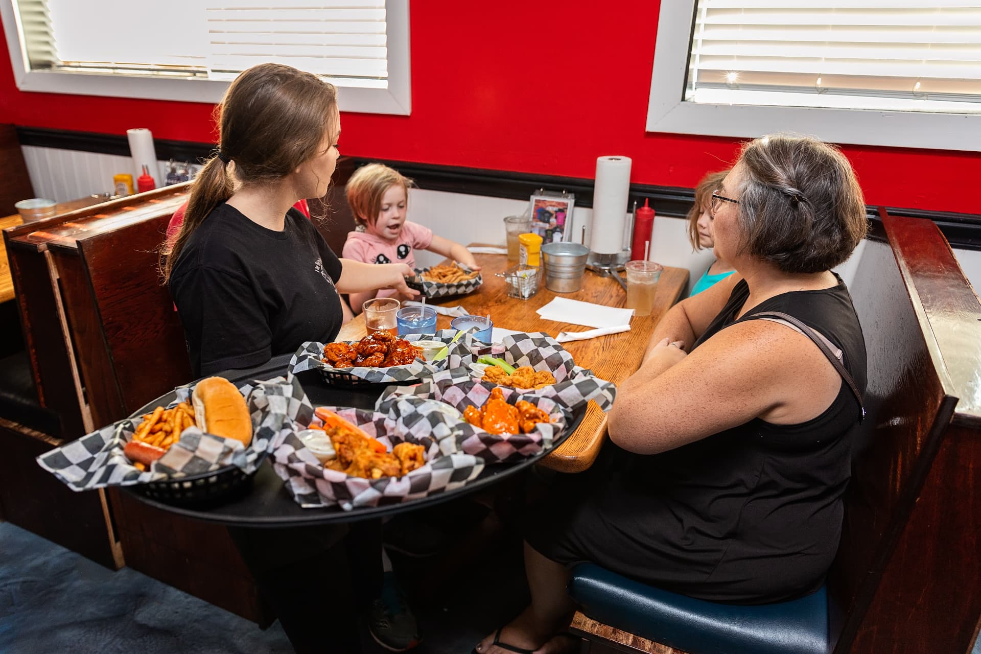 A server delivering trays of wings and fries to a family at Colley Ave in Norfolk