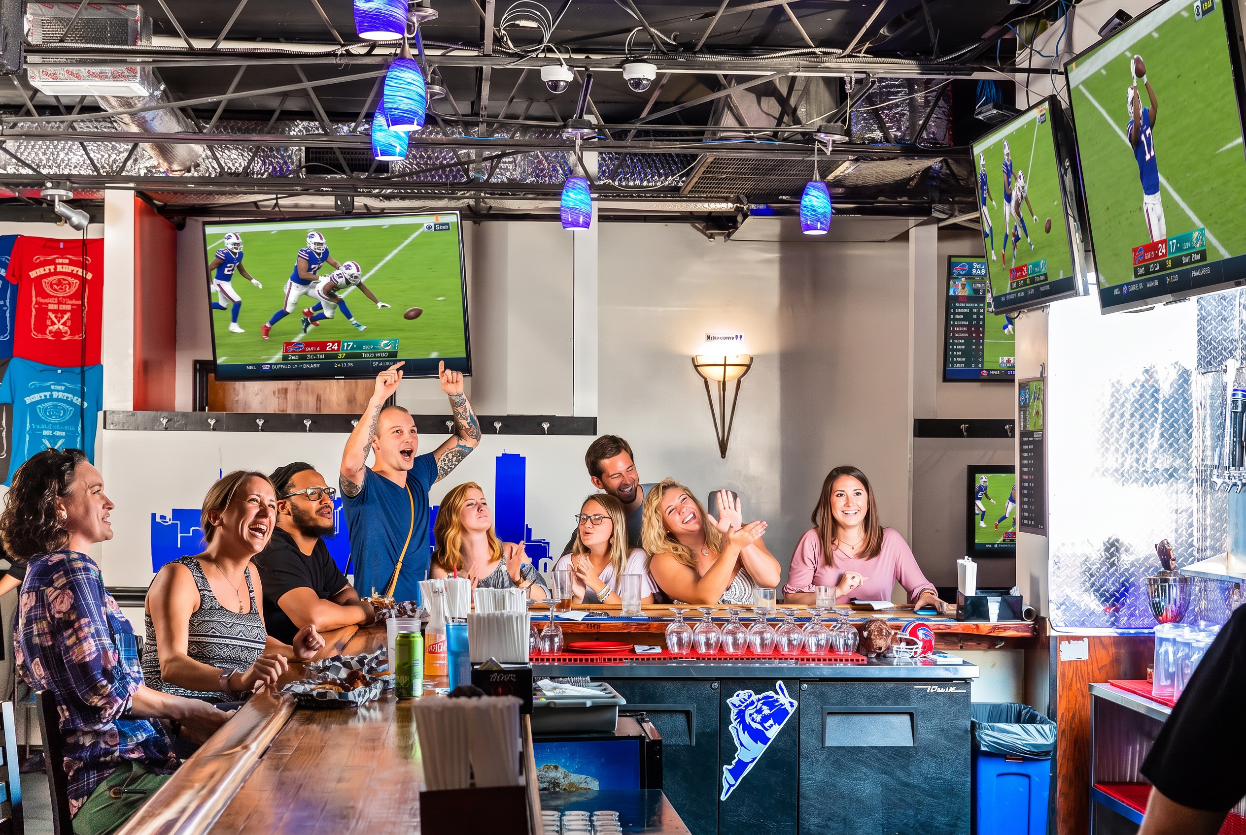 Guests cheering at the bar at Colley Ave with football on the TVs overhead
