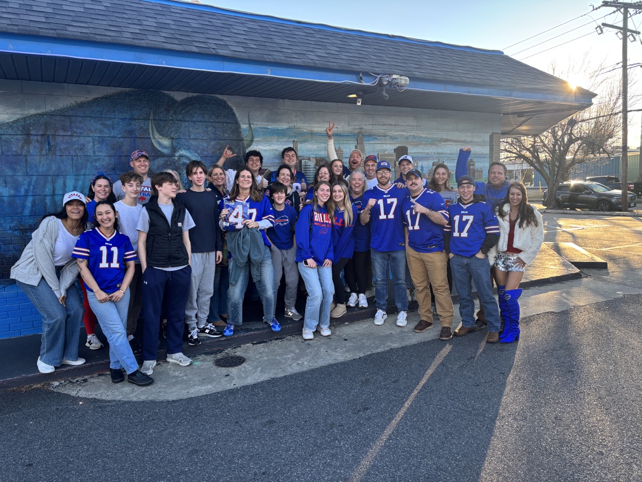 A crowd of Bills fans and team members outside the Colley Avenue buffalo mural