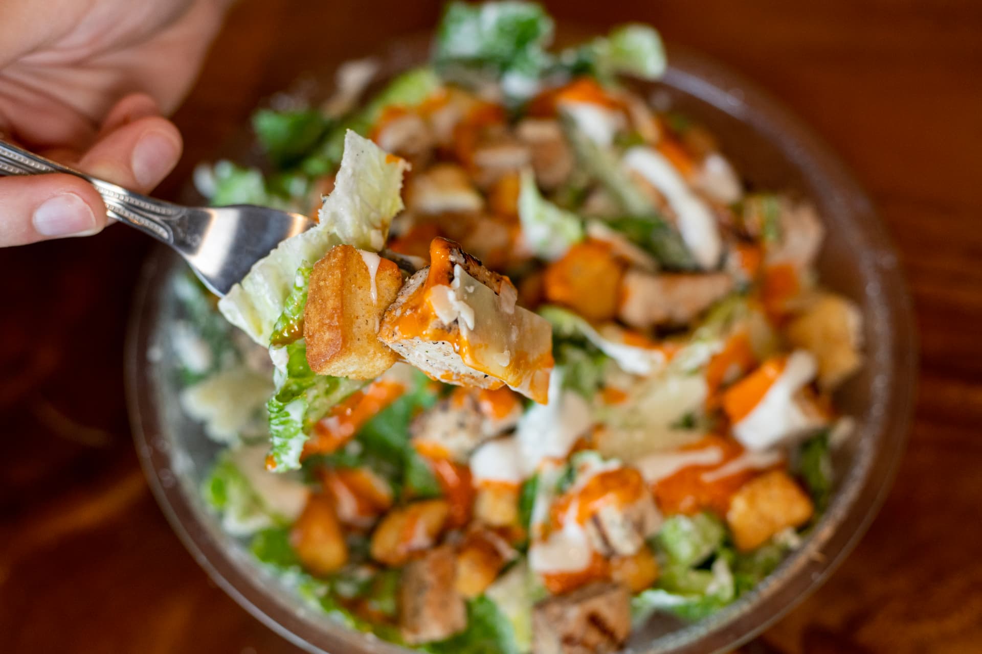 Forkful of Buffalo Chicken Caesar salad with croutons and parmesan