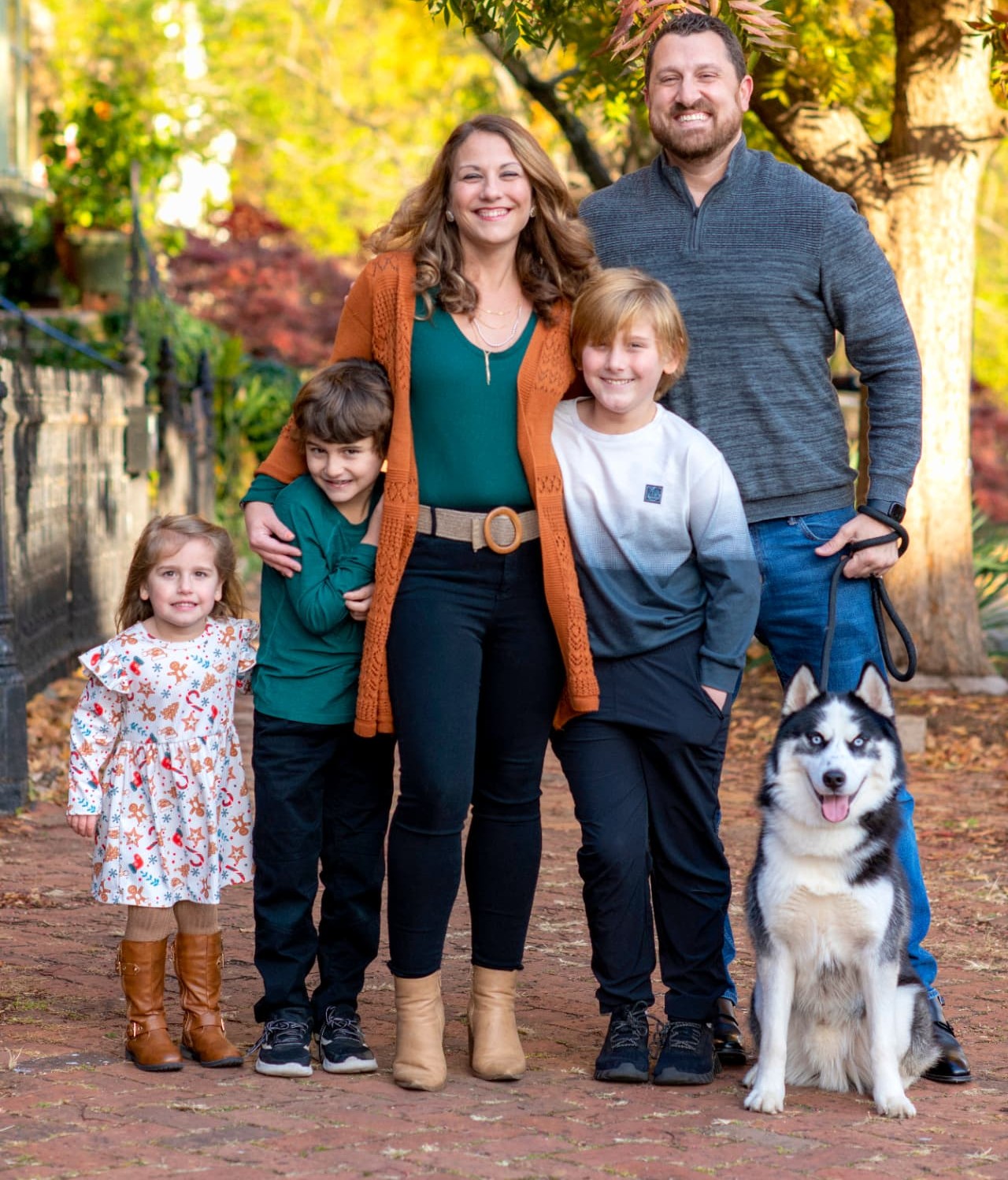 Steph and Russ Gilbert with their three children and their husky on a fall afternoon