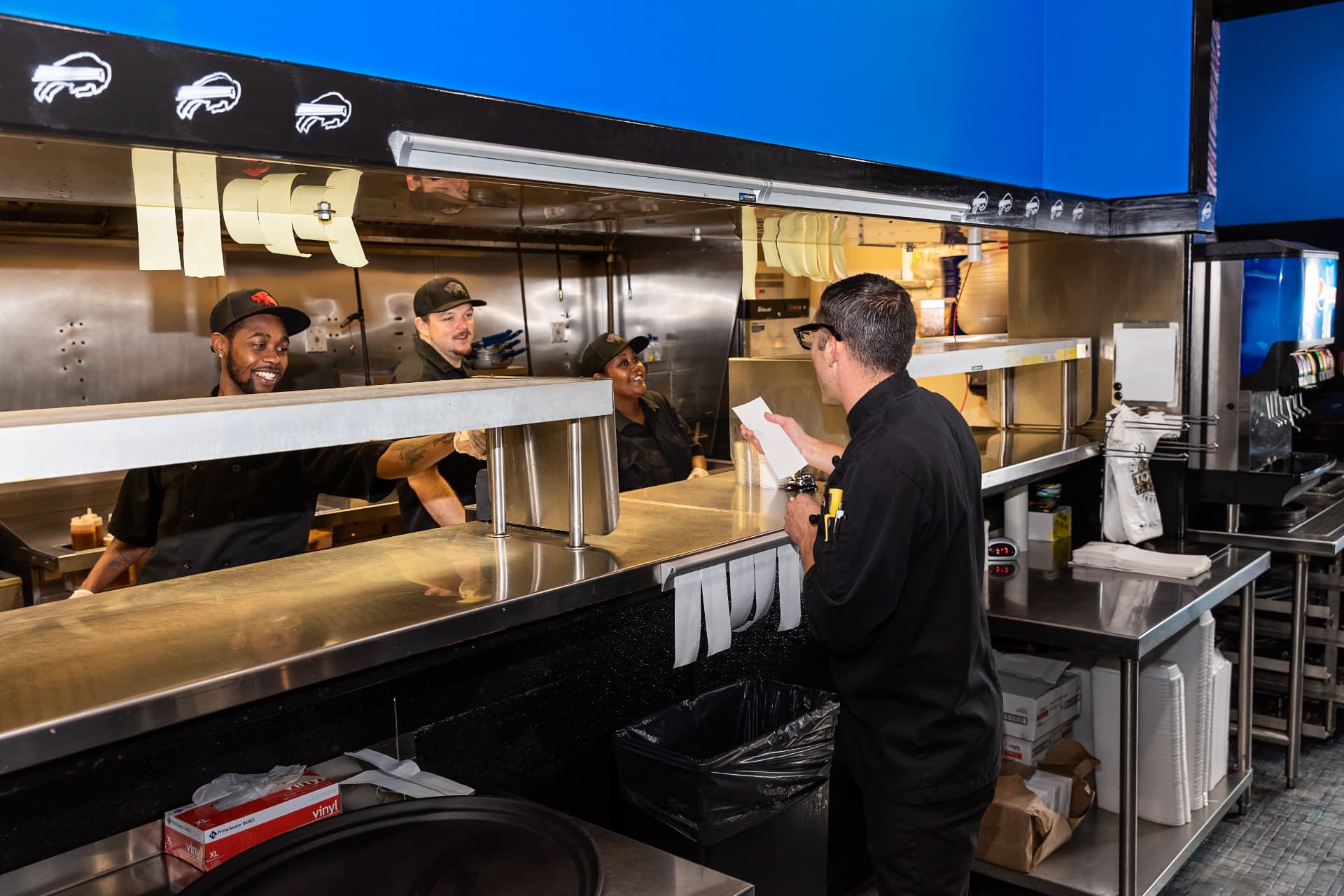 Kitchen crew handing off a fresh order at the expo window at The Dirty Buffalo Little Creek