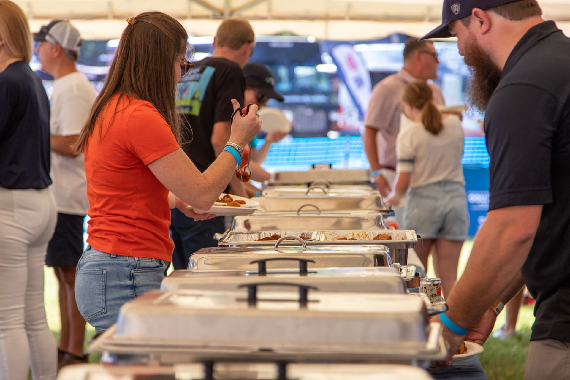 Guests serving themselves from a Dirty Buffalo catering buffet line under a tent