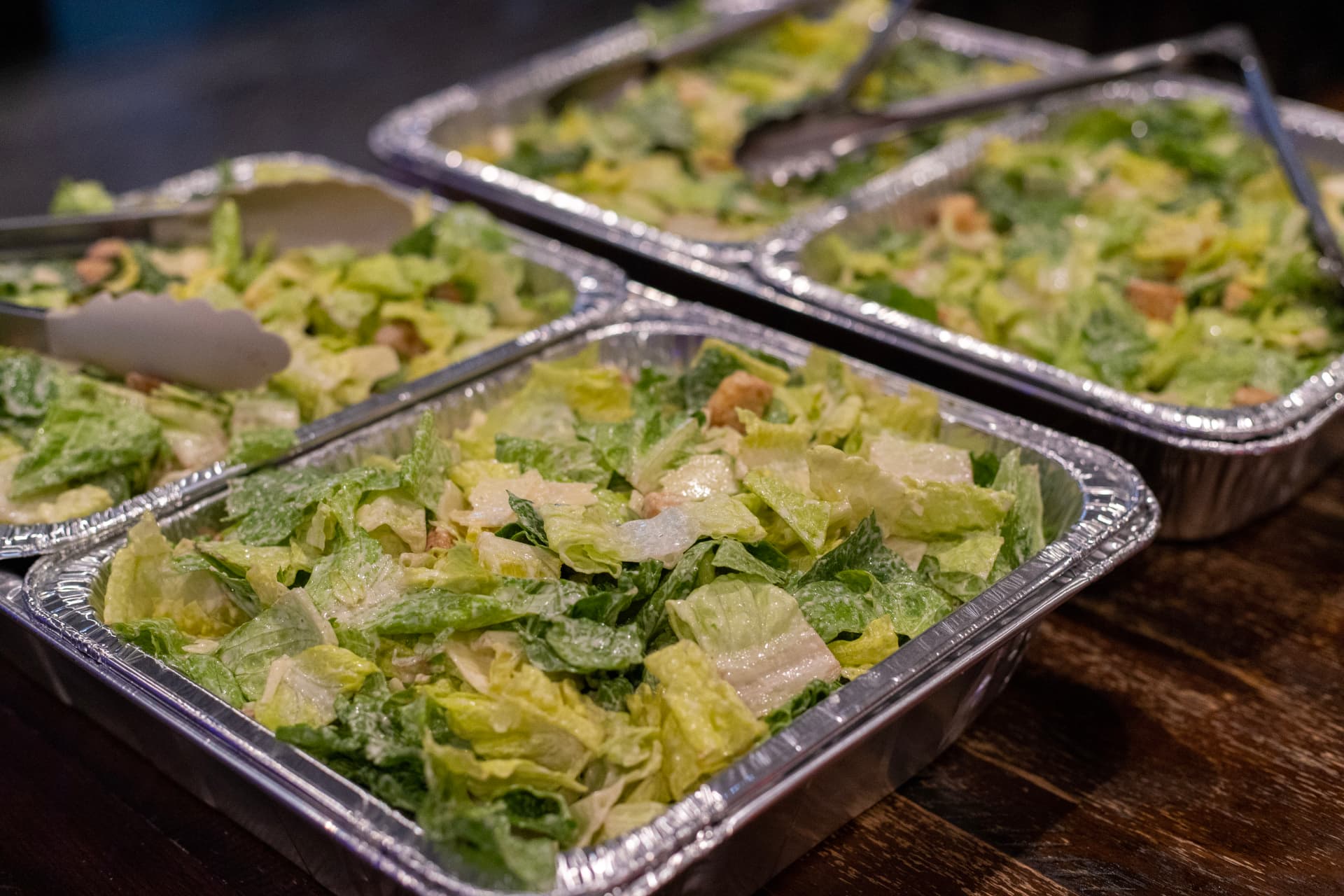 Catering trays of fresh Caesar salad with croutons and tongs