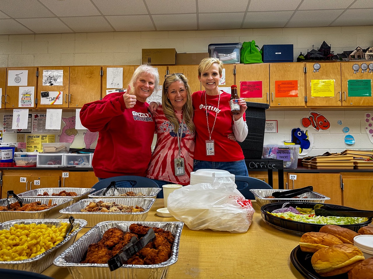 Teachers gathered around trays of Dirty Buffalo wings and sides donated to their school