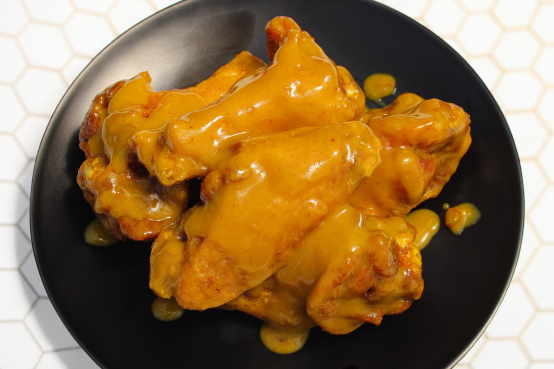 Honey Mustard wings on a black plate at The Dirty Buffalo