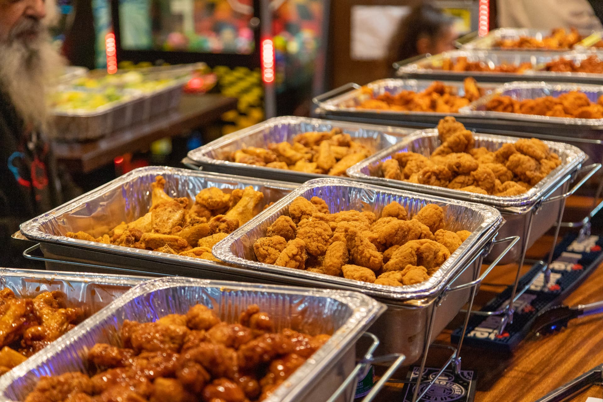 Chafing trays of boneless wings, bone-in wings and sauced wings lined up for a catering order