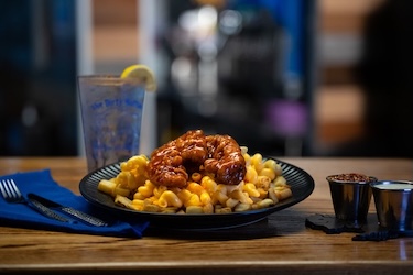 Dirty Chick plate with saucy chicken tenders over mac-n-cheese and home fries