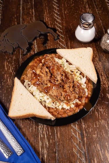 Dirty Pig plate with pulled pork over baked beans and coleslaw