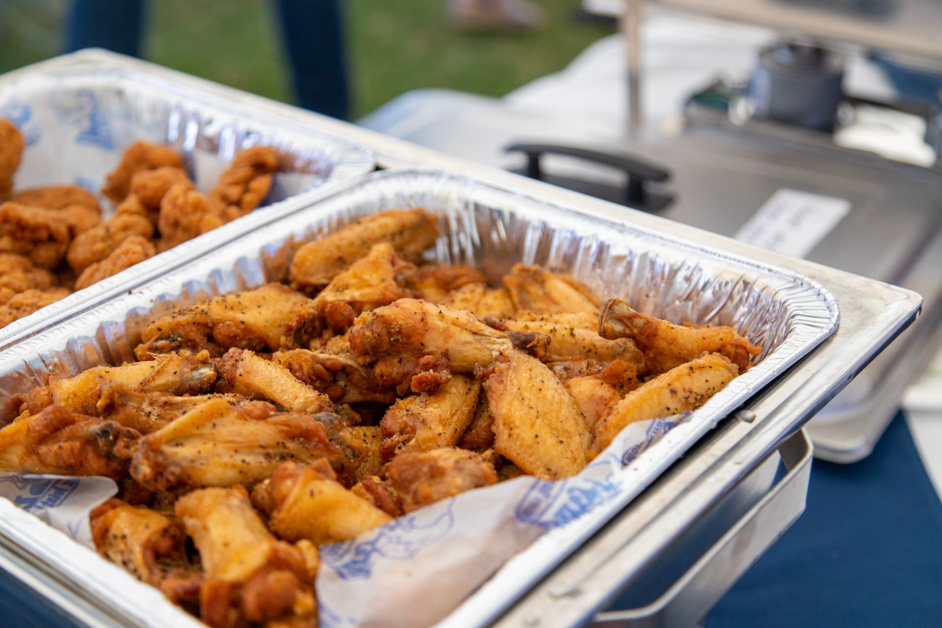 Tray of dry-rub bone-in wings in Dirty Buffalo paper at an outdoor catering event