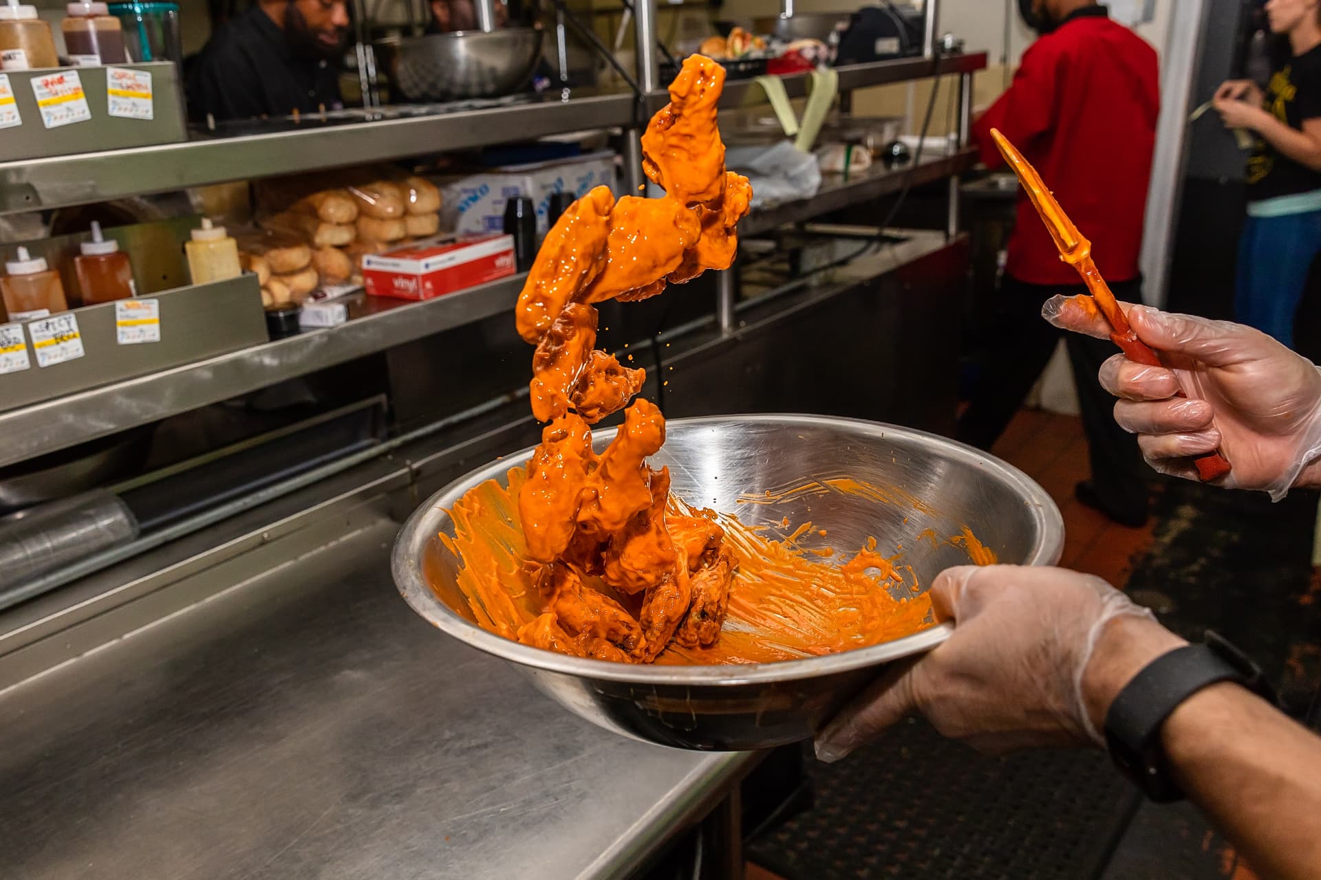 Wings being tossed in sauce at The Dirty Buffalo