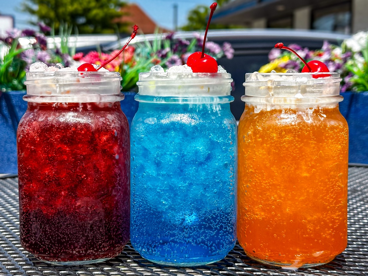 Three Dirty Sodas in mason jars topped with whipped cream and cherries