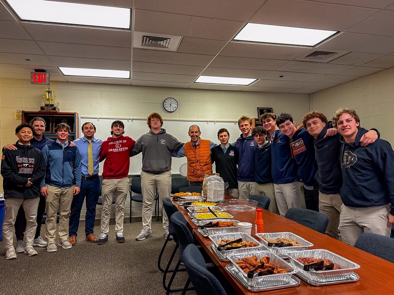 High school team and coaches around a conference table of Dirty Buffalo wing trays