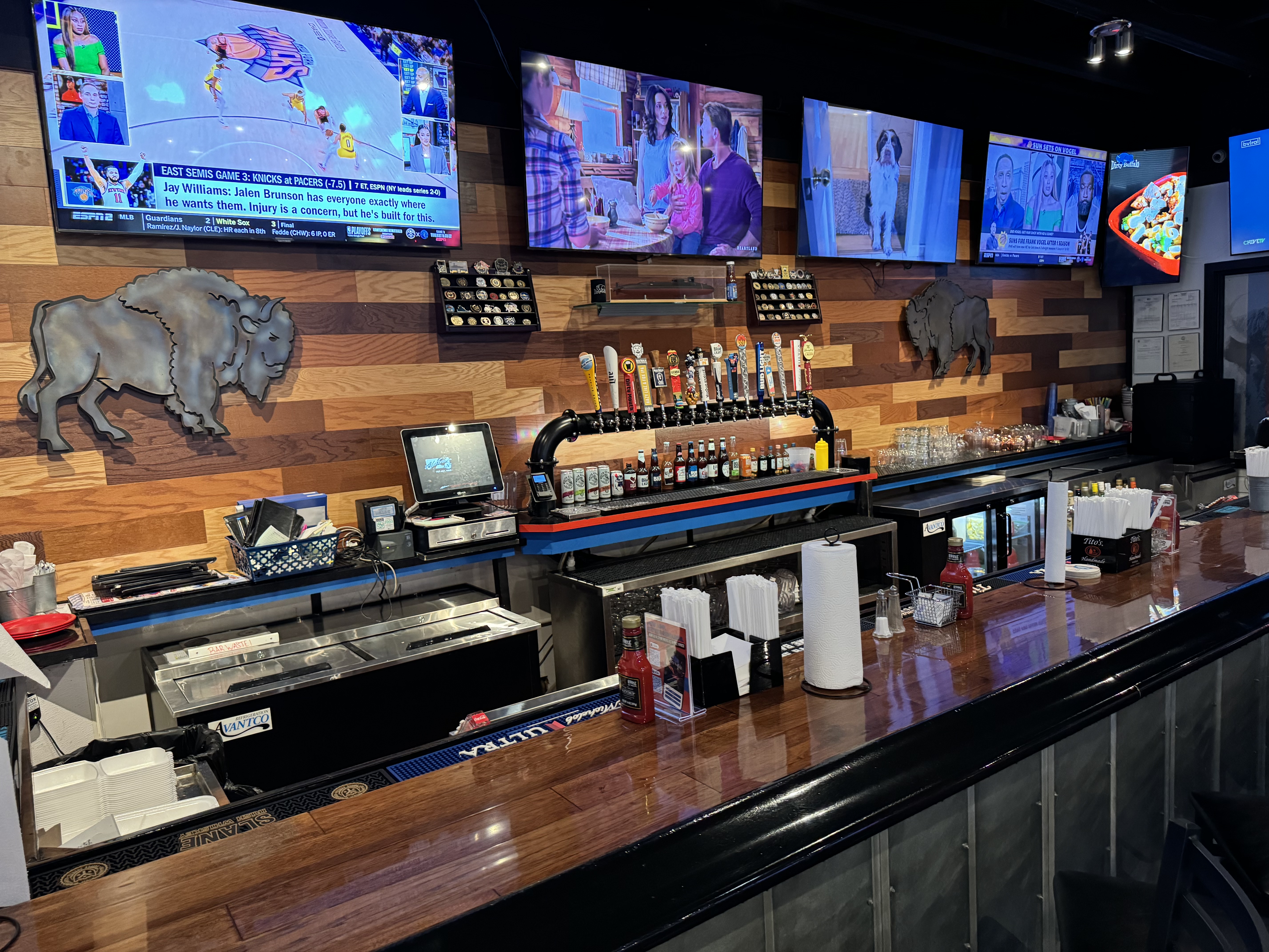 The blue-lit draft tap wall behind the bar at The Dirty Buffalo