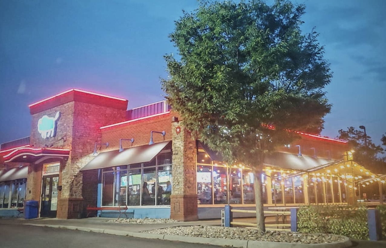 The Dirty Buffalo on E Little Creek Rd in Norfolk at dusk, neon roofline lit over the string-lit patio