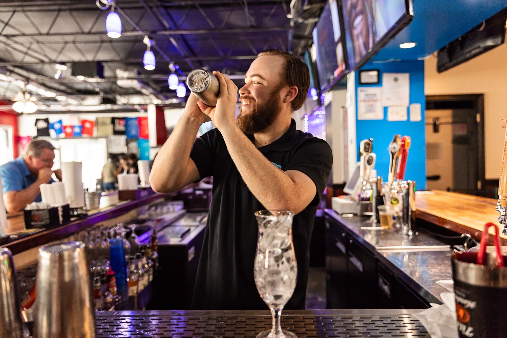 A Dirty Buffalo bartender shaking a cocktail behind the bar at Colley Ave